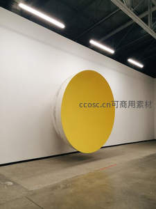 现代展厅内悬浮的黄色圆形艺术装置