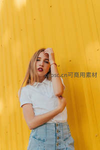 金发少女倚靠明黄墙前凝视镜头