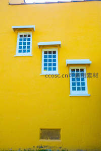 三扇白窗镶嵌于明亮黄墙之上