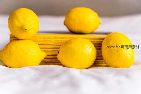 五颗柠檬围绕黄色书本静置白布之上