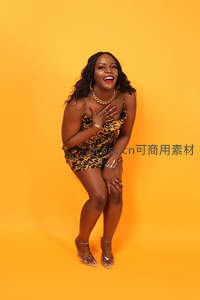 身着豹纹裙的女性在橙色背景前展现自信笑容