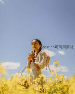 少女置身金黄花海，嗅闻花朵享受春日