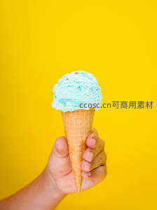 手持蓝色冰淇淋甜筒在明黄背景前