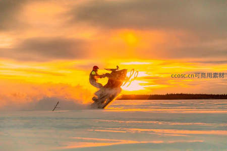 雪地摩托疾驰于日落金辉之中