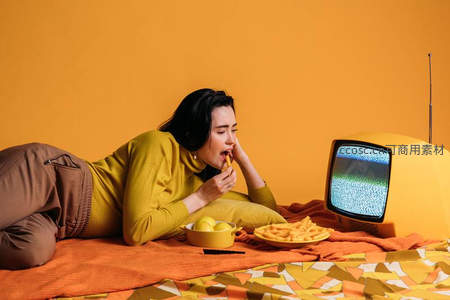 女子躺卧吃薯条看电视享受闲暇