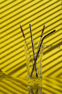 玻璃杯中的黑色吸管与黄色光影