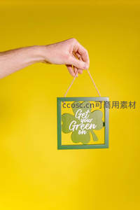 手握绿色四叶草挂饰，黄色背景显活力