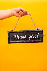 手提黑板牌写着感谢你，暖黄背景温馨
