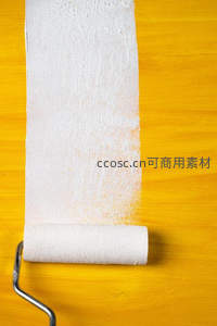滚筒刷涂抹白色涂料，留下纹理痕迹于木纹黄墙
