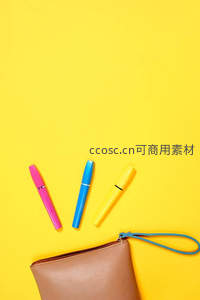 黄色背景上的彩色笔与手拿包