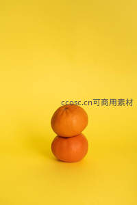 两颗橙子叠放于黄色背景