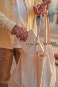 老人双手提着帆布袋取出一本小书