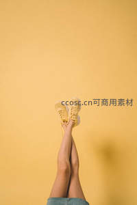 黄色背景下向上伸展的双腿与运动鞋