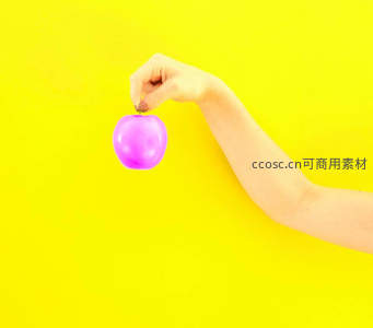 手握梦幻紫色苹果悬于明黄背景
