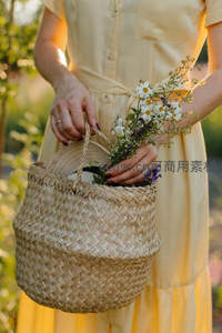 女子手提草编篮盛满雏菊与薰衣草花束