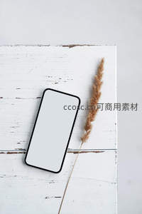 手机与干草静置于旧木桌面