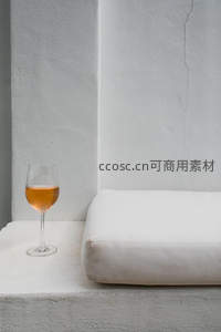 一杯橙酒静置于白色石阶旁，简约而惬意