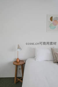 极简卧室一角，木桌铜灯与白床相映成趣