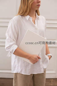白衬衫女子手持文件夹侧身站立