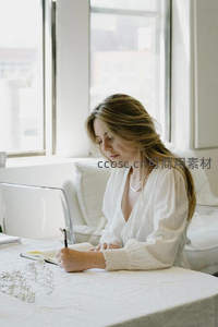 女子窗边伏案书写笔记场景