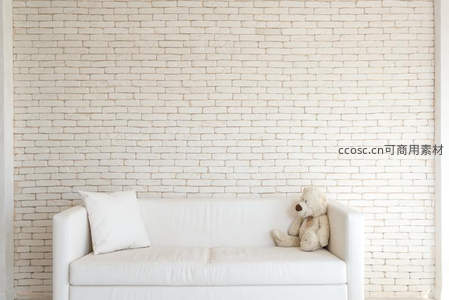 白色沙发配泰迪熊，砖墙背景温馨舒适