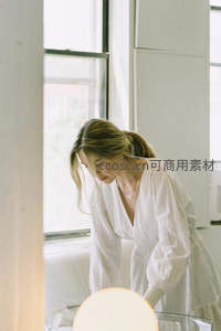 窗边女子身着白裙低头沉思