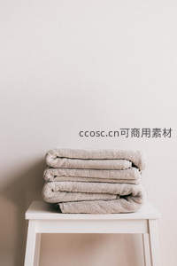 米色毛巾整齐叠放在白色小凳上的极简场景