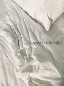 阳光洒落的凌乱白色床品特写