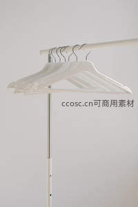 一排整齐的白色衣架悬挂在衣架杆上