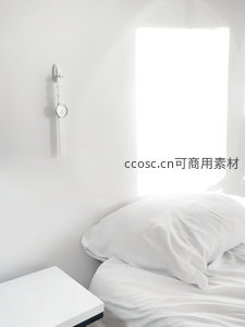 极简卧室中阳光洒在白色床铺上