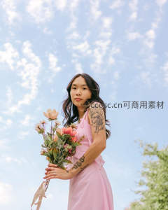 粉色裙装女子手持花束仰望蓝天