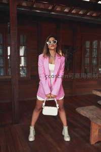 粉西装白短裤女郎在木质阳台自信摆拍