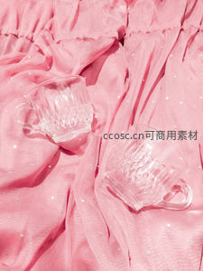 粉色布景上的透明玻璃杯静物特写