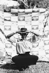 草地上女子以手遮阳凝视远方