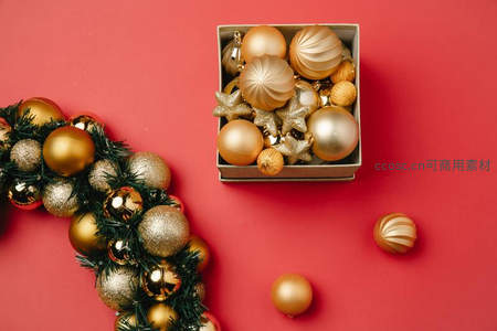 红色背景上金色圣诞装饰球与花环