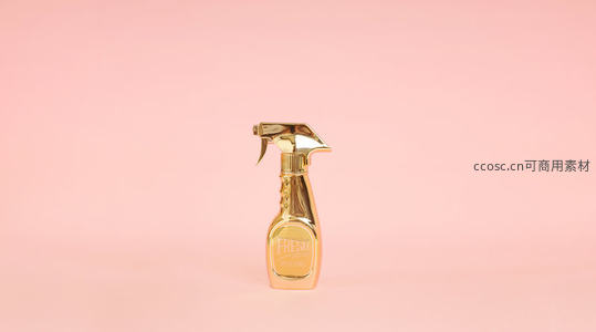 金色喷雾瓶在粉色背景下的极简主义展示