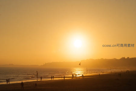 海滩日落剪影，人们漫步享受金色余晖