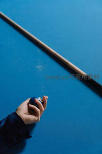 手握台球杆与蓝色球的特写