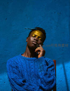 蓝墙前沉思的金色面庞青年