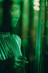 绿光下的女子手持酒杯若有所思