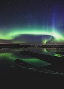 湖面倒影极光璀璨，小舟静泊星夜如梦