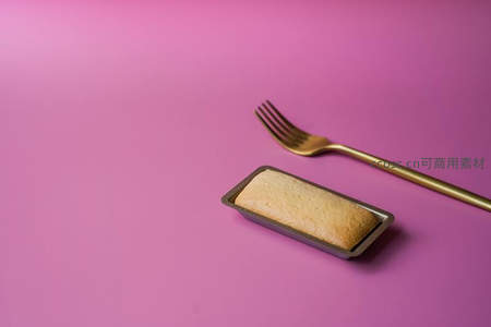 粉色背景上的金色叉子与小蛋糕