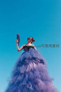 蓝紫纱裙女子仰望蓝天持扇起舞