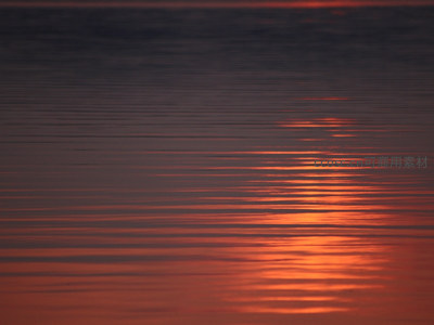 夕阳余晖映照平静湖面的暖色倒影