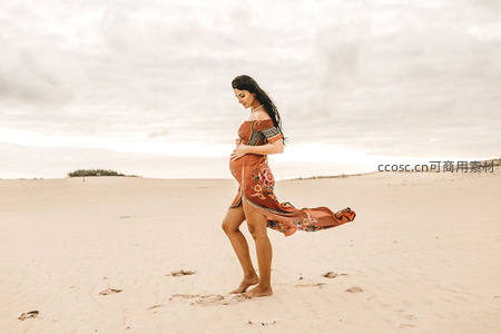 孕妇赤足沙滩漫步，飘逸长裙随风轻舞