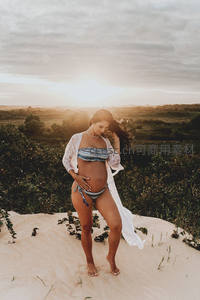 孕妈沙丘夕阳下轻抚腹部