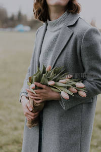 灰衣女子怀抱粉色郁金香