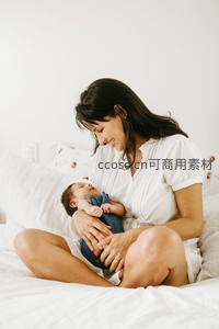 母亲床上微笑凝视熟睡宝宝