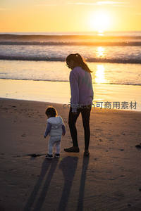 夕阳下母子漫步沙滩剪影