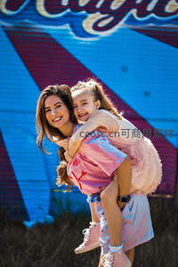 户外嬉戏母女相拥，彩色墙前欢乐飞扬